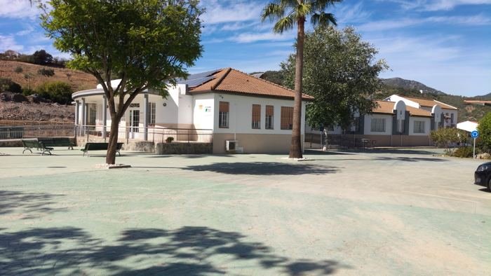 Edificio del Centro de Día Ocupacional visto desde el exterior, con árboles y una palmera en primer plano