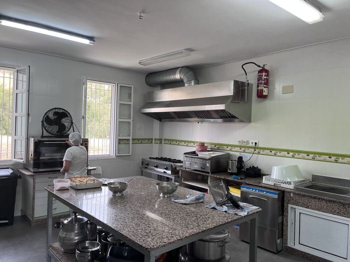 Cocina del centro con campana extractora, mesa de acero y una profesional trabajando