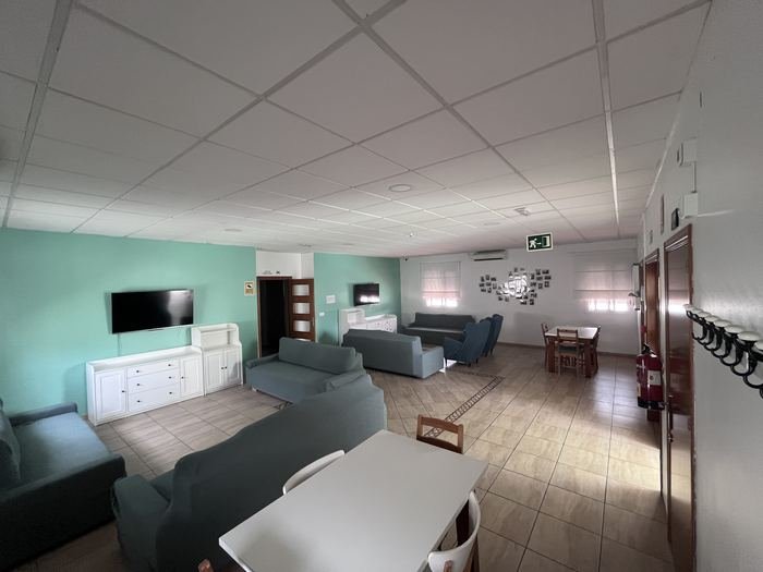 Salón de la residencia con sofás, televisión y zona de comedor